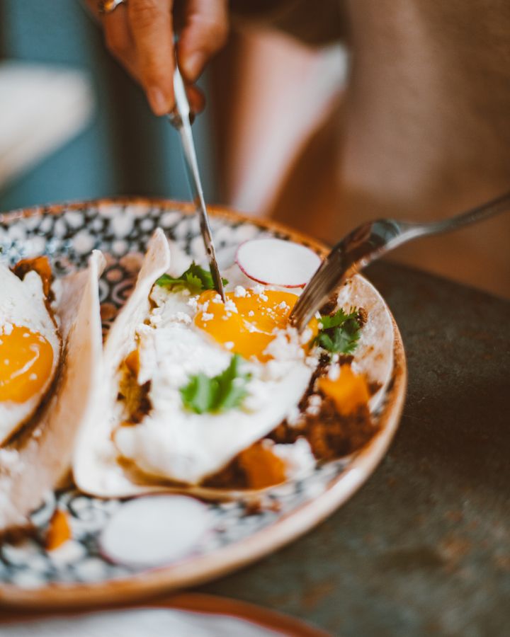 Breakfast tacos with fried eggs, cotija and cilantro on a painted plate