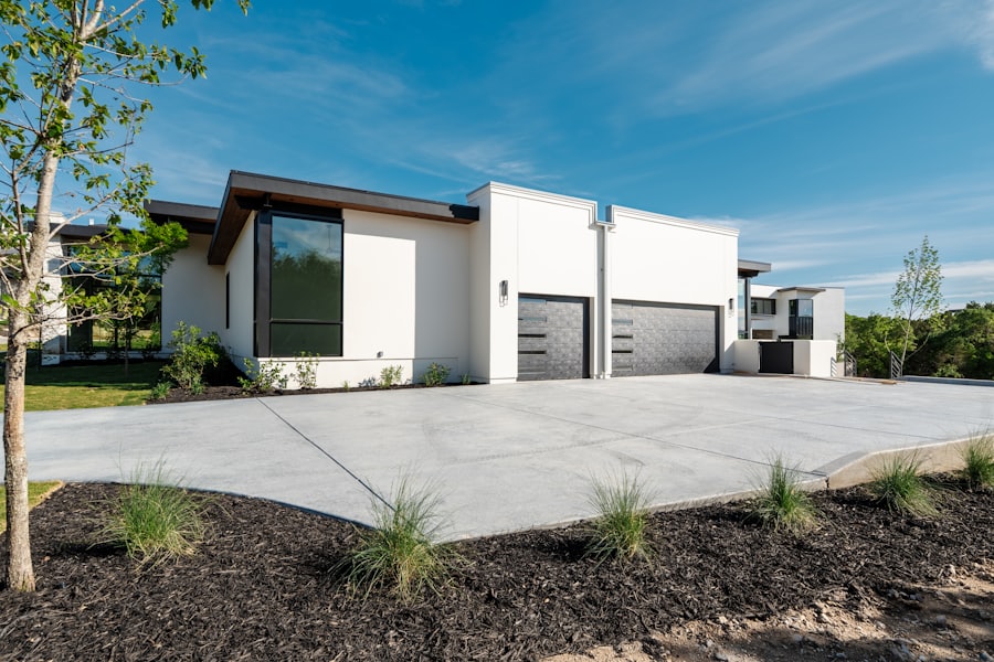 A wide finished residential concrete driveway with saw cut control joints running to a double garage