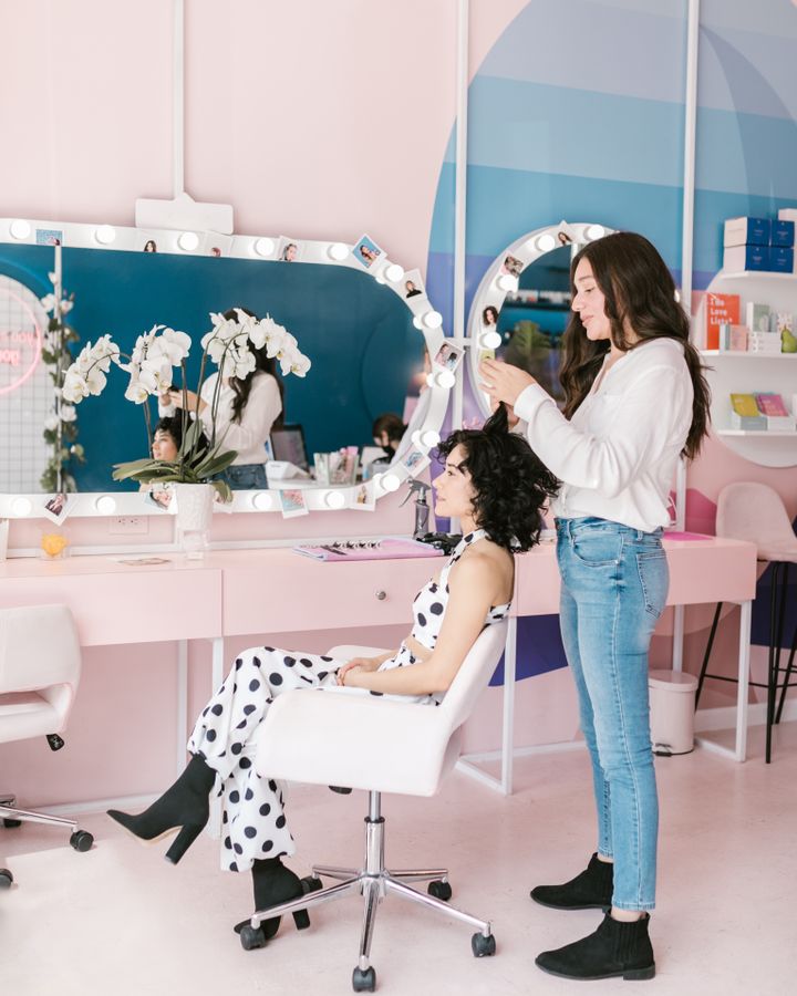A client seated at the mirror while her stylist finishes a blowout