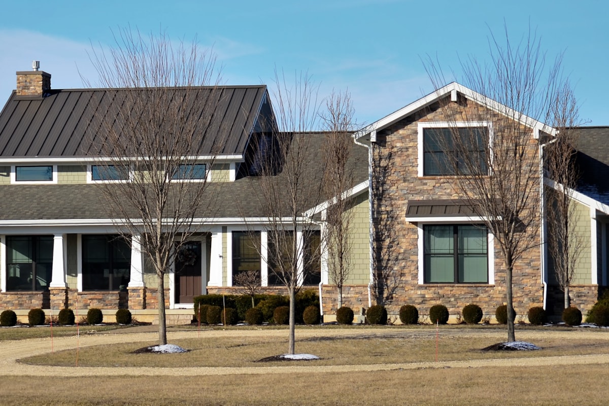 Stone piers and a dark standing seam metal roof over the covered entry of the Boerne Ridge house