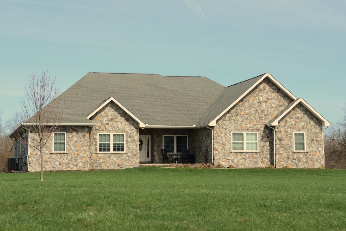 A single level stone house sitting low and wide on an open lot at Garden Ridge