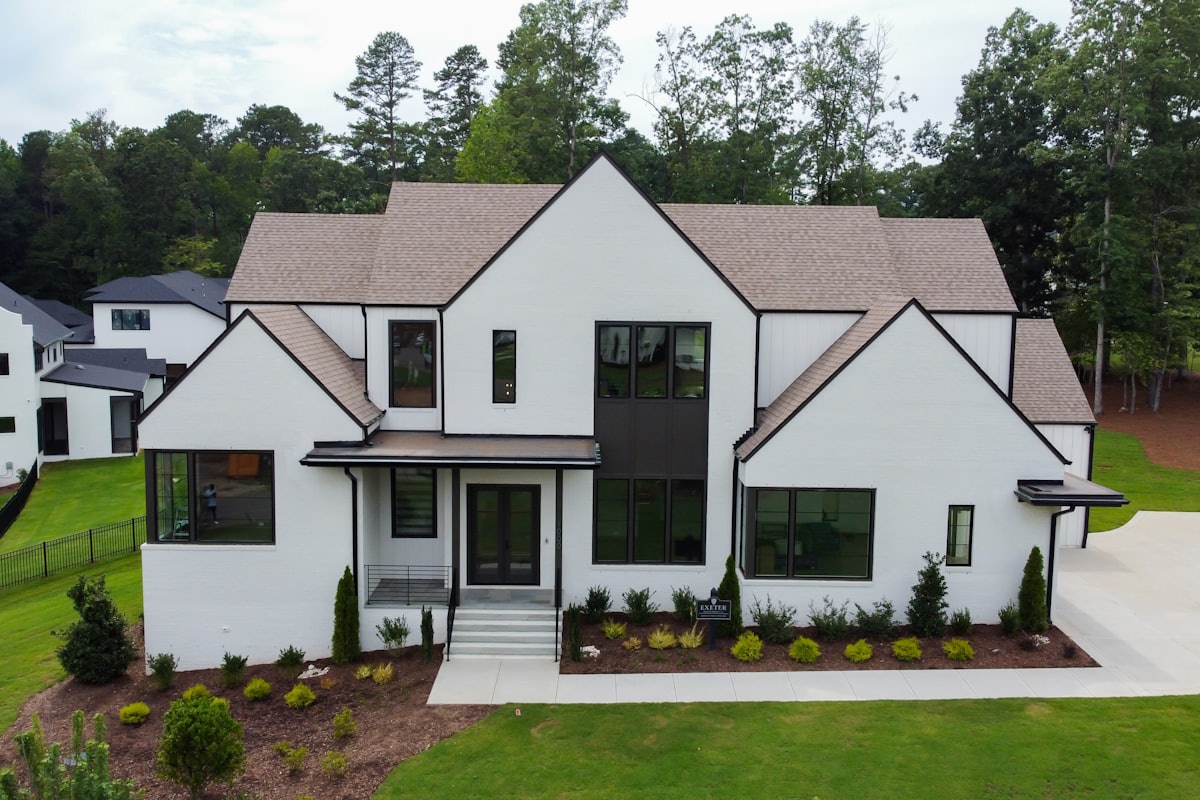 A rebuilt white painted brick house with black steel windows on an established tree lined street