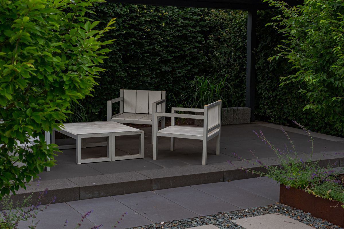 Stone paved courtyard terrace with a clipped hedge and gravel joints