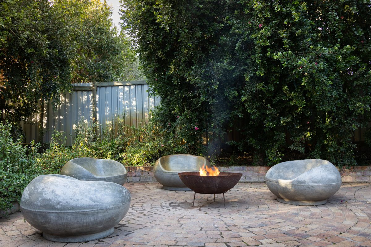 Dry set limestone courtyard with a fire bowl and low planted seat walls