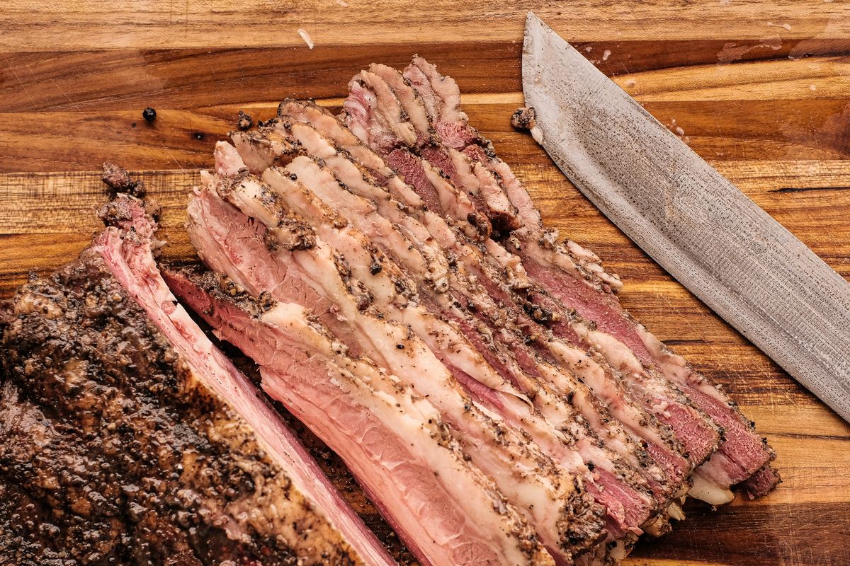 Peppered brisket sliced across the grain on a wooden board